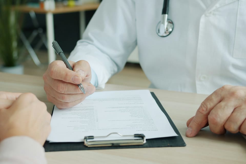 Healthcare professional writing on a form during a conversation