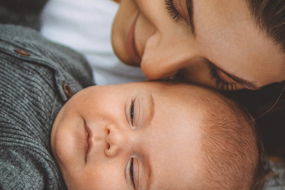 Parent resting beside a sleeping baby