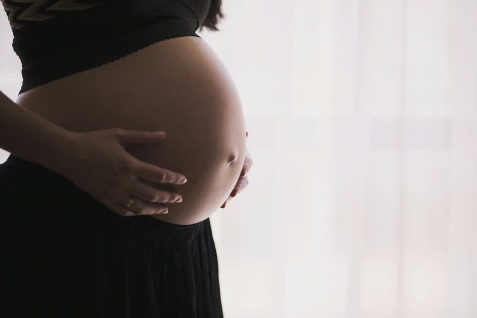 Pregnant person resting a hand on their abdomen