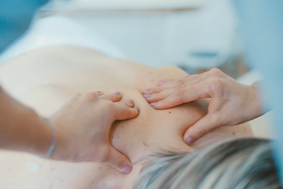 Hands applying massage to a person's upper back